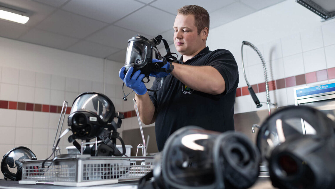 Atemschutzgerätewart bestückt Korb mit Atemschutzmasken zur Reinigung im TopClean M von Meiko  Atemschutzgerätewart bestückt Korb mit Atemschutzmasken zur Reinigung im TopClean M von Meiko